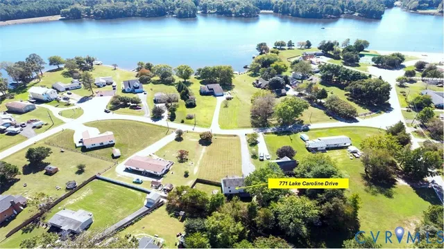an aerial view of a house with a lake boats and trees all around