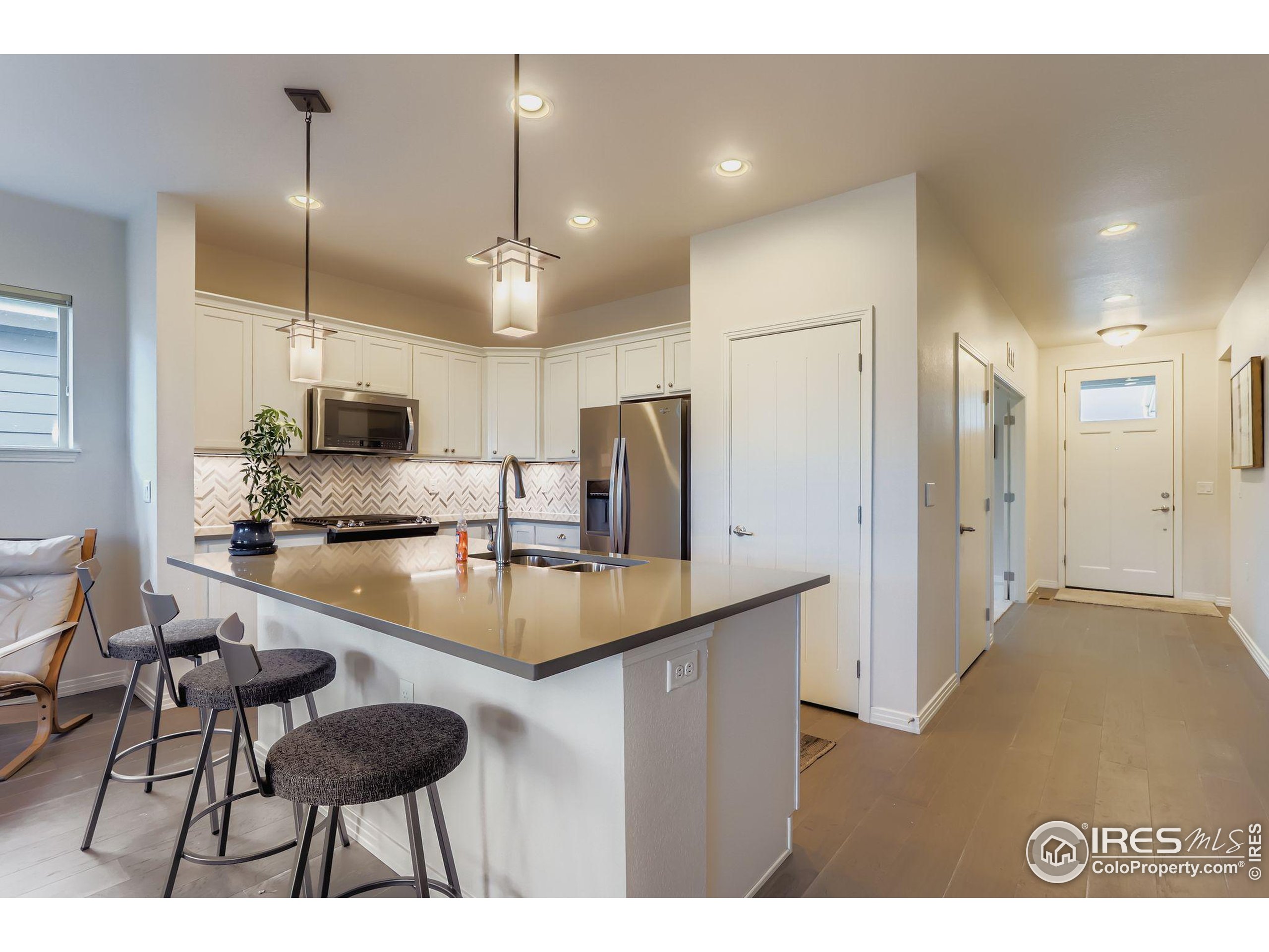 671 Brennan Circle Erie, CO 80516 - Photo 8 of 26 a kitchen with stainless steel appliances kitchen island a chandelier