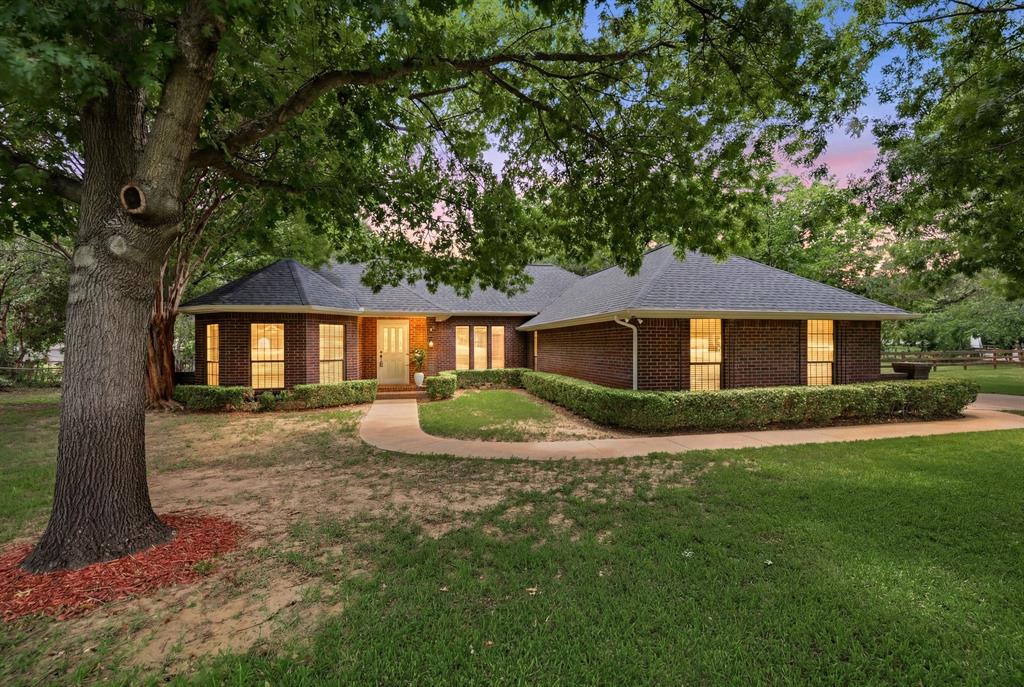 1805 Renfro Road Colleyville, TX 76034 - Photo 1 of 40 Brick exterior residence featuring a dark shingle roof, established landscaping, a paved walkway, and mature trees