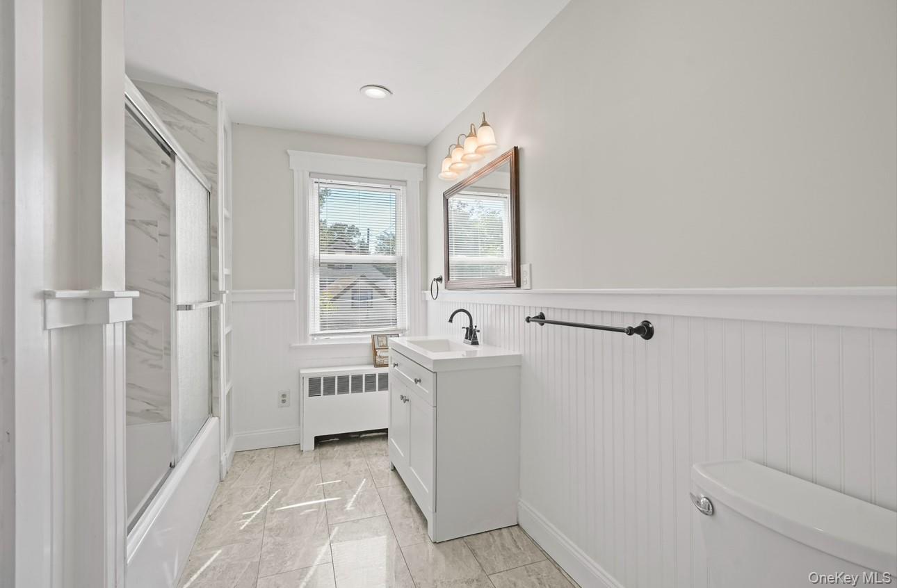 17 Edgar Place Port Chester, NY 10573 - Photo 9 of 18 Full bathroom featuring a wainscoted wall, vanity, radiator, shower / bath combination with glass door, and wood walls