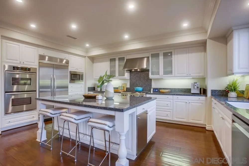 7535 Circulo Sequoia Carlsbad, CA 92009 - Photo 5 of 57 a kitchen with stainless steel appliances granite countertop a table chairs sink and cabinets