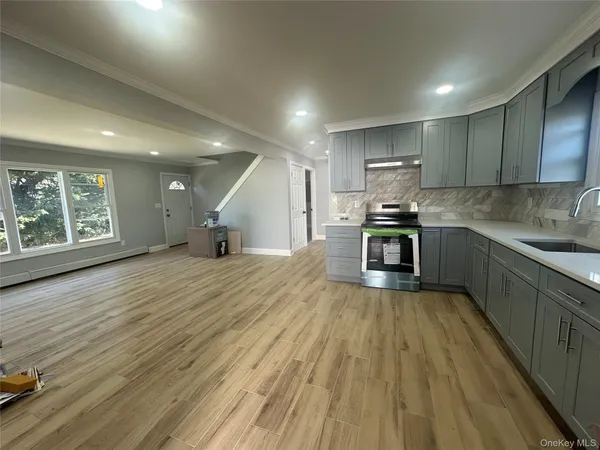 a kitchen with stainless steel appliances granite countertop a stove a sink dishwasher and a refrigerator with wooden floor