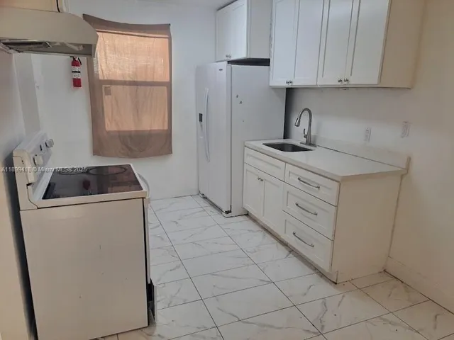 a kitchen with cabinets appliances and a window