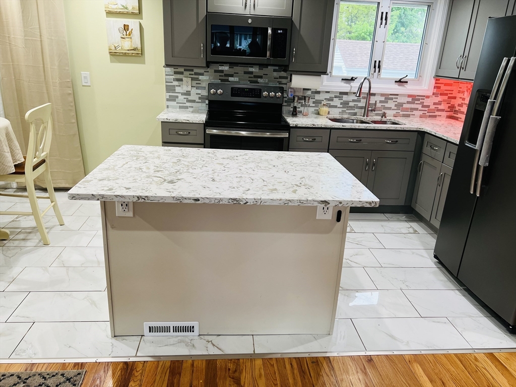 18 Shirley Road Springfield, MA 01109 - Photo 20 of 39 a kitchen with kitchen island granite countertop a sink a stove top oven a counter space and cabinets