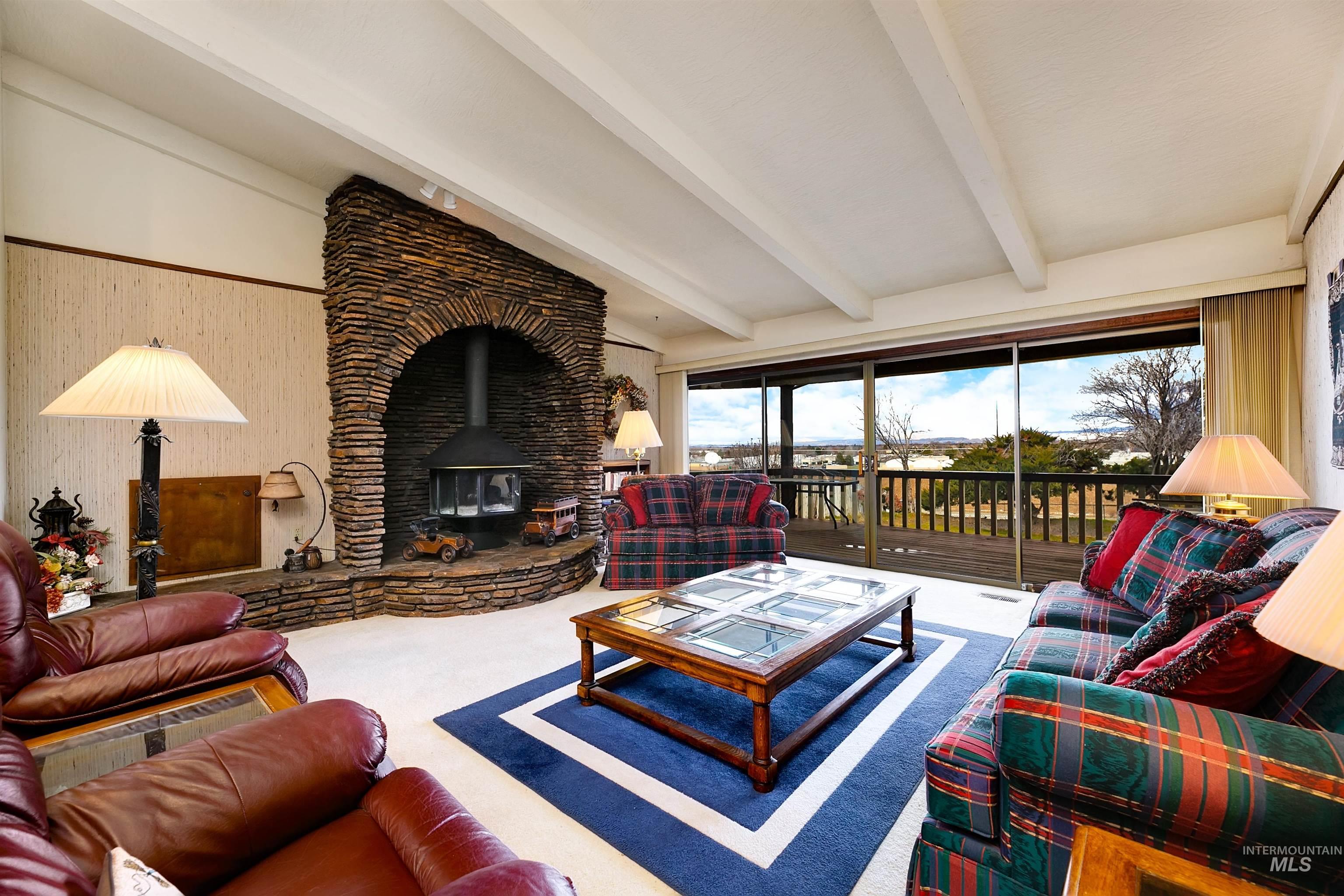 10030 West Stardust Drive Boise, ID 83709 - Photo 19 of 50 Carpeted living area with a wood stove and vaulted ceiling with beams