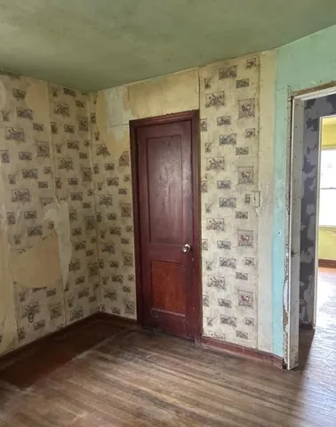 an empty room with wooden door and hallway