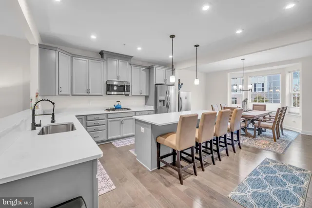 a kitchen with stainless steel appliances granite countertop a dining table chairs and white cabinets