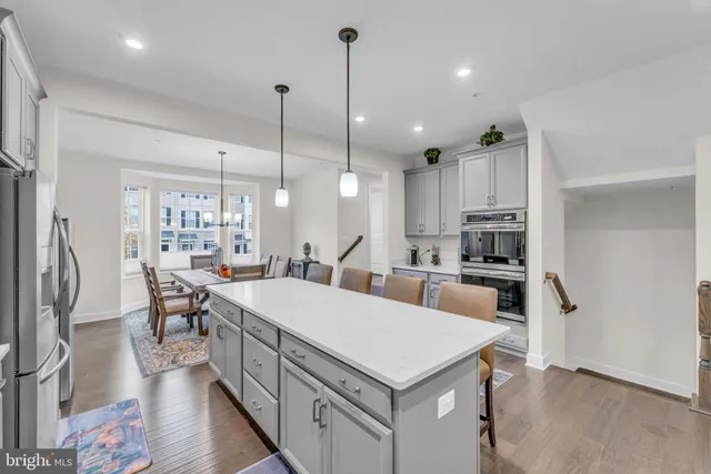 a large kitchen with stainless steel appliances a refrigerator a stove a sink dishwasher a dining table and chairs with wooden floor