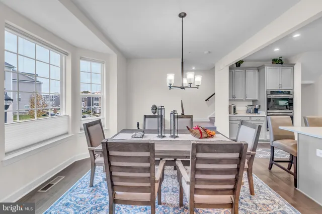 a kitchen with stainless steel appliances granite countertop a refrigerator a sink dishwasher a dining table and chairs with wooden floor