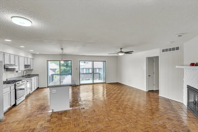 an empty room with windows and chandelier fan