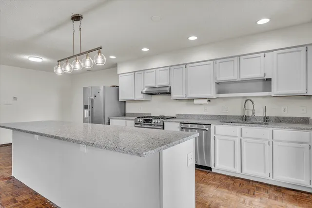 a kitchen with kitchen island granite countertop a sink a center island a stove and cabinets