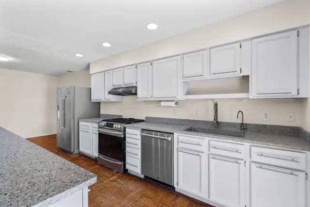 a kitchen with granite countertop white cabinets and stainless steel appliances