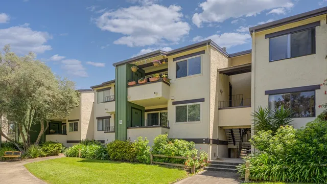 a view of a white house with many windows next to a yard