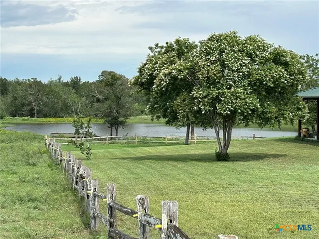 a view of a lake with a yard and large trees
