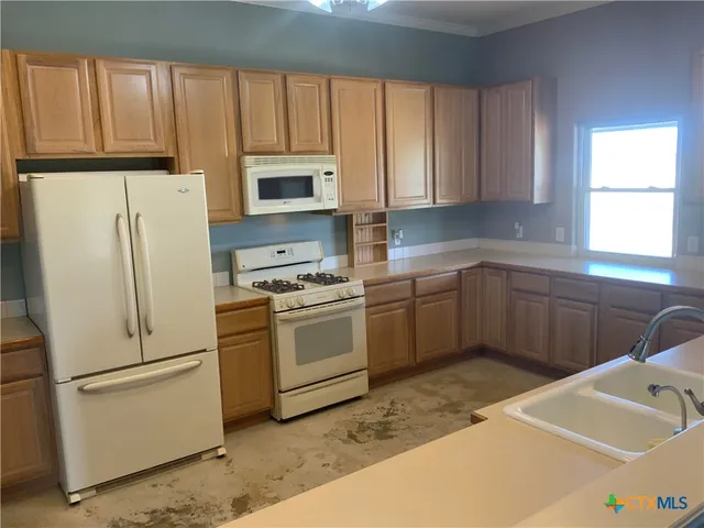 a kitchen with a sink stove top oven and refrigerator