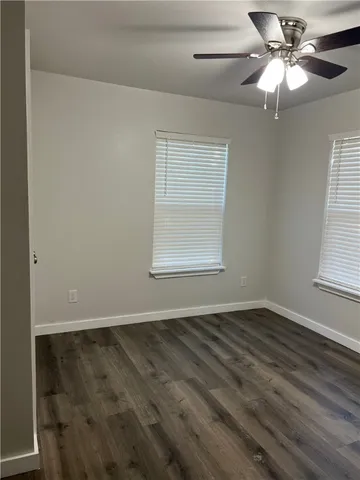 a view of an empty room with window and chandelier fan
