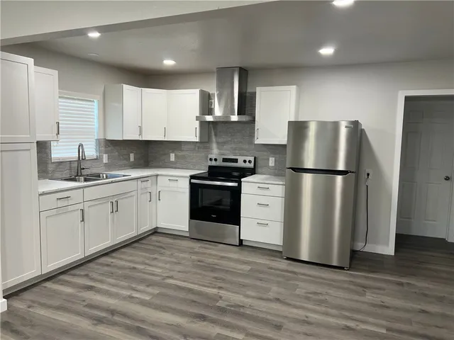 a kitchen with a sink a refrigerator and white cabinets