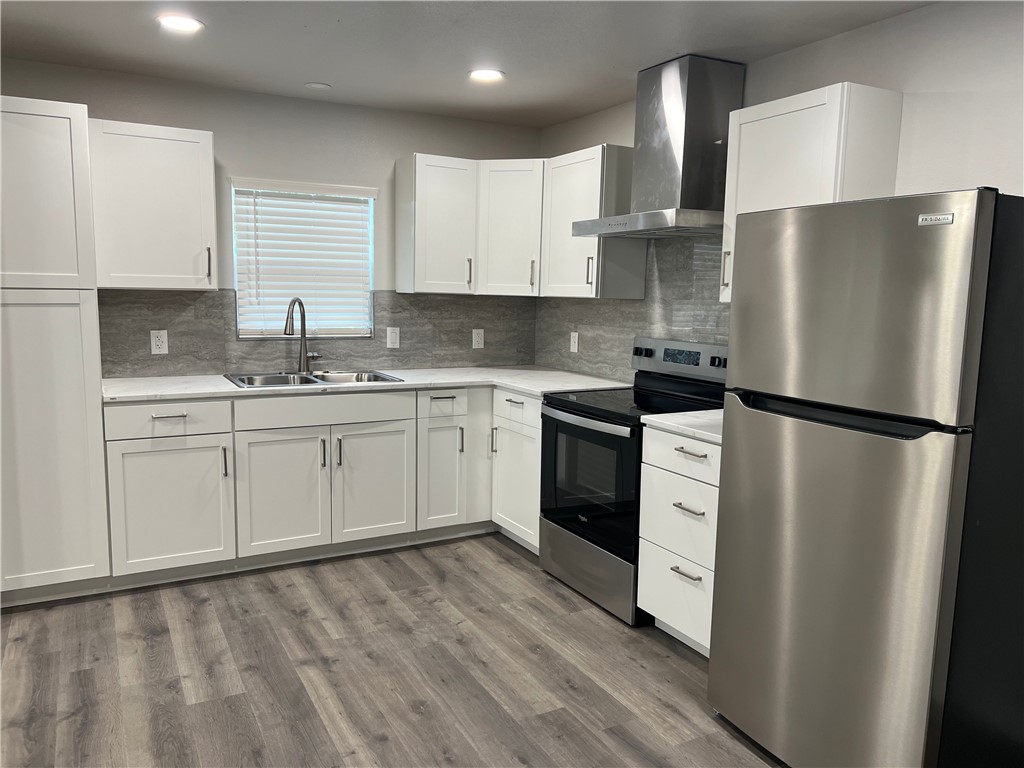 912 North Rife Street Aransas Pass, TX 78336 - Photo 7 of 23 a kitchen with a sink a refrigerator and white cabinets