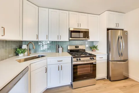 a kitchen with cabinets stainless steel appliances and wooden floor