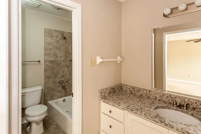 a bathroom with a granite countertop sink toilet mirror and bathtub