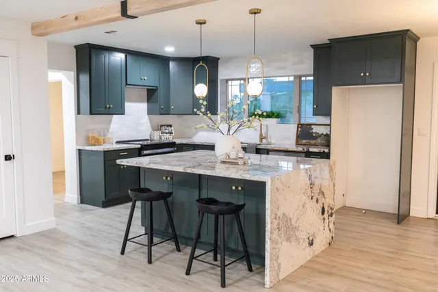 a kitchen with stainless steel appliances kitchen island a table chairs in it and wooden floors