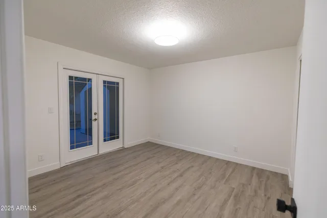 a view of an empty room with wooden floor and closet