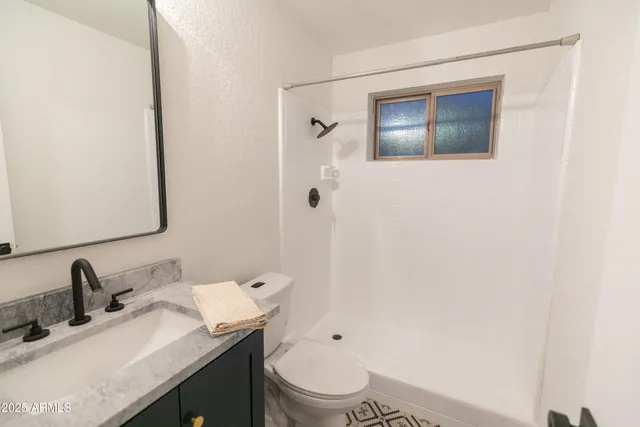 a bathroom with a granite countertop toilet sink and mirror