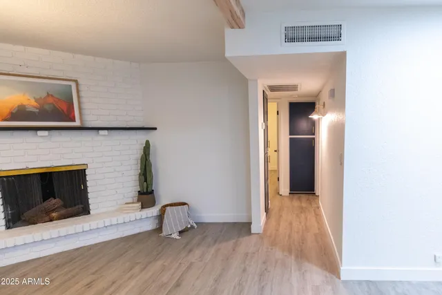 a view of an empty room with wooden floor and a fireplace