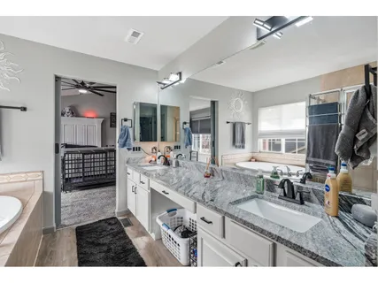 a spacious bathroom with a granite countertop double vanity sink a mirror and a shower