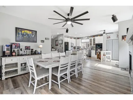 a dining room with wooden floor a ceiling fan a wooden table and chairs