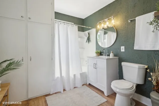 a bathroom with a toilet sink vanity and mirror