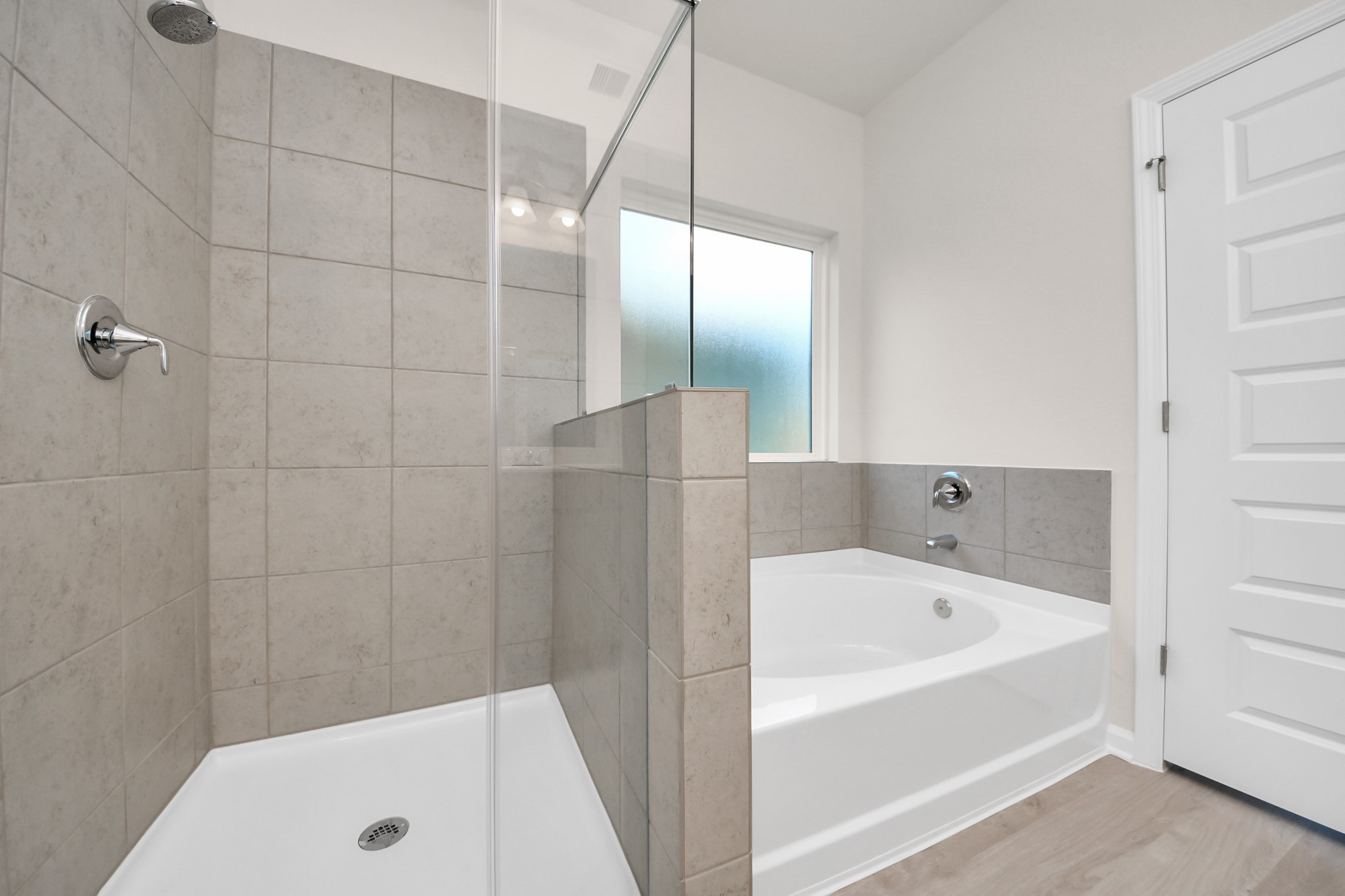 15523 Fathom Line Way Houston, TX 77053 - Photo 26 of 39 Elegant primary bathroom featuring a separate shower and soaking tub, neutral tile finishes, and natural light from a frosted window. Designed with both comfort and functionality in mind.