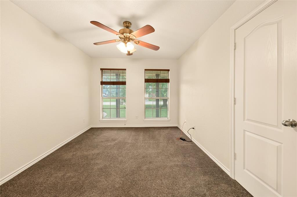 2105 Ridgewood Drive Bridgeport, TX 76426 - Photo 23 of 27 Grey carpeted interior space featuring two windows with horizontal blinds, a ceiling fan with integrated lighting, and a paneled interior door to closet.
