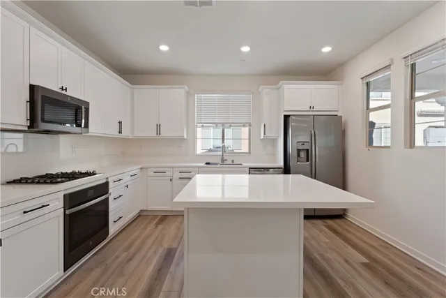 a kitchen with cabinets appliances a sink and a window