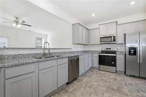 a kitchen with granite countertop a sink stove and refrigerator