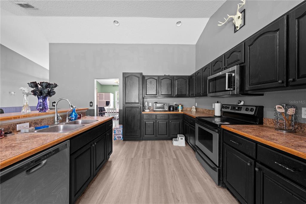 1965 Mustang Court St. Cloud, FL 34771 - Photo 11 of 33 a kitchen with stainless steel appliances kitchen island granite countertop a sink a stove top oven a counter space and cabinets