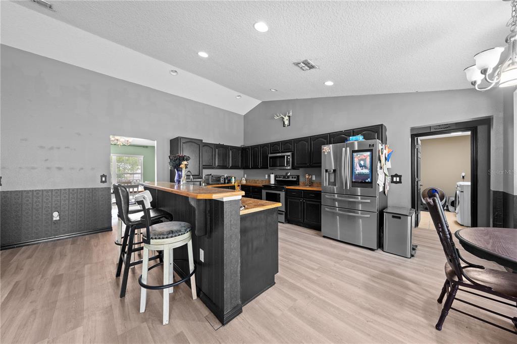 1965 Mustang Court St. Cloud, FL 34771 - Photo 13 of 33 a kitchen with stainless steel appliances kitchen island granite countertop a table chairs cabinets and wooden floor