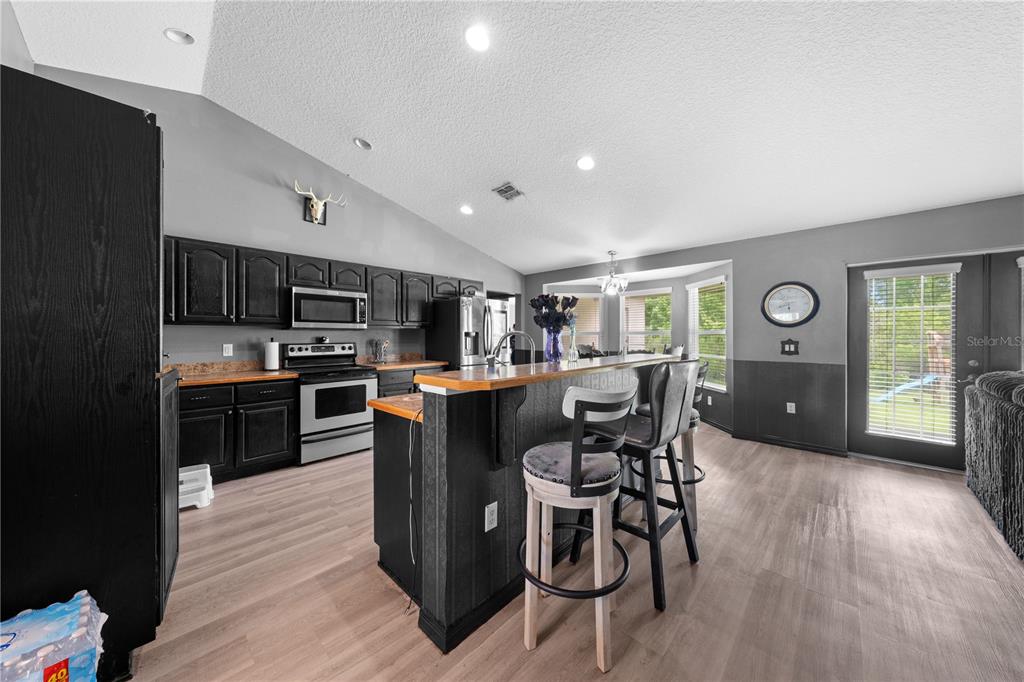 1965 Mustang Court St. Cloud, FL 34771 - Photo 15 of 33 a kitchen with stainless steel appliances kitchen island granite countertop a table chairs and a refrigerator
