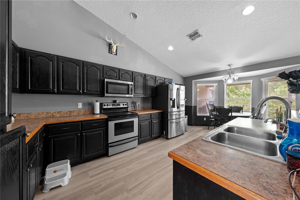 1965 Mustang Court St. Cloud, FL 34771 - Photo 16 of 33 a kitchen with stainless steel appliances granite countertop wooden cabinets a sink dishwasher a stove and a refrigerator with wooden floor