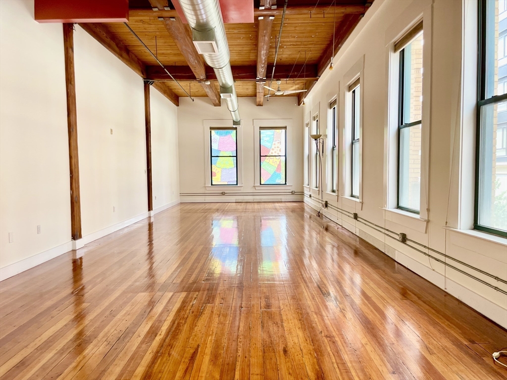 49 Munroe Street, Unit 201 Lynn, MA 01901 - Photo 3 of 14 a view of an empty room with wooden floor and a window