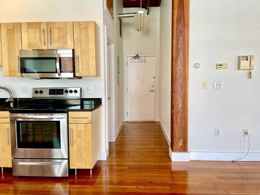 49 Munroe Street, Unit 201 Lynn, MA 01901 - Photo 9 of 14 a view of a kitchen with stainless steel appliances wooden floor and cabinets