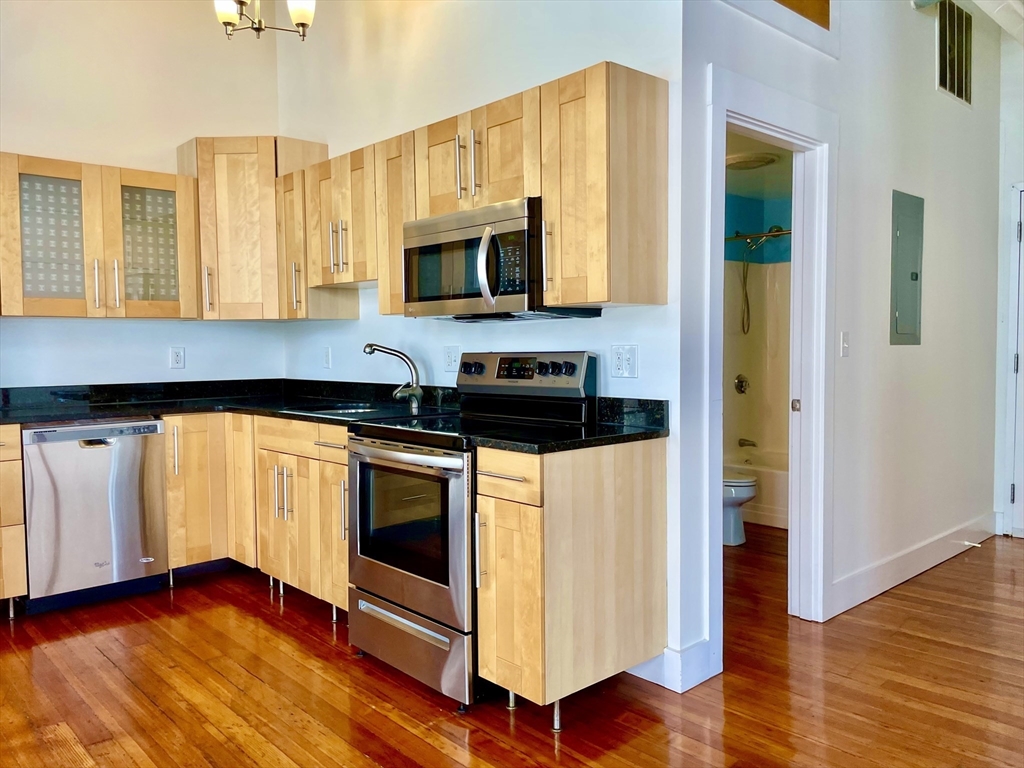 49 Munroe Street, Unit 201 Lynn, MA 01901 - Photo 10 of 14 a kitchen with stainless steel appliances granite countertop a stove a sink and a microwave