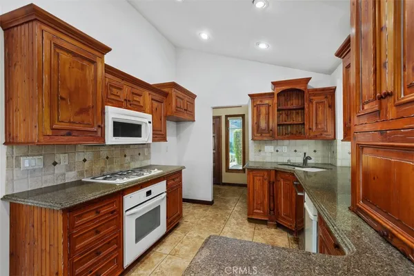 a kitchen with stainless steel appliances granite countertop a stove a sink and a microwave