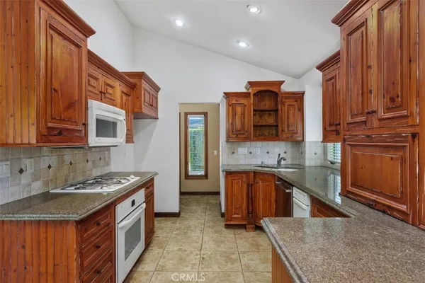 a kitchen with stainless steel appliances granite countertop a stove a sink dishwasher and a refrigerator