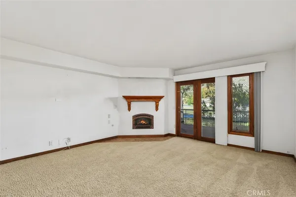 an empty room with chandelier fan and windows