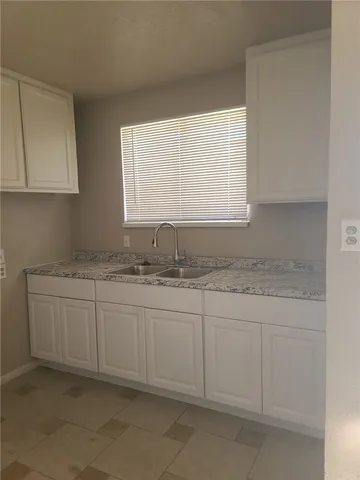 a bathroom with granite countertop white cabinets and a sink