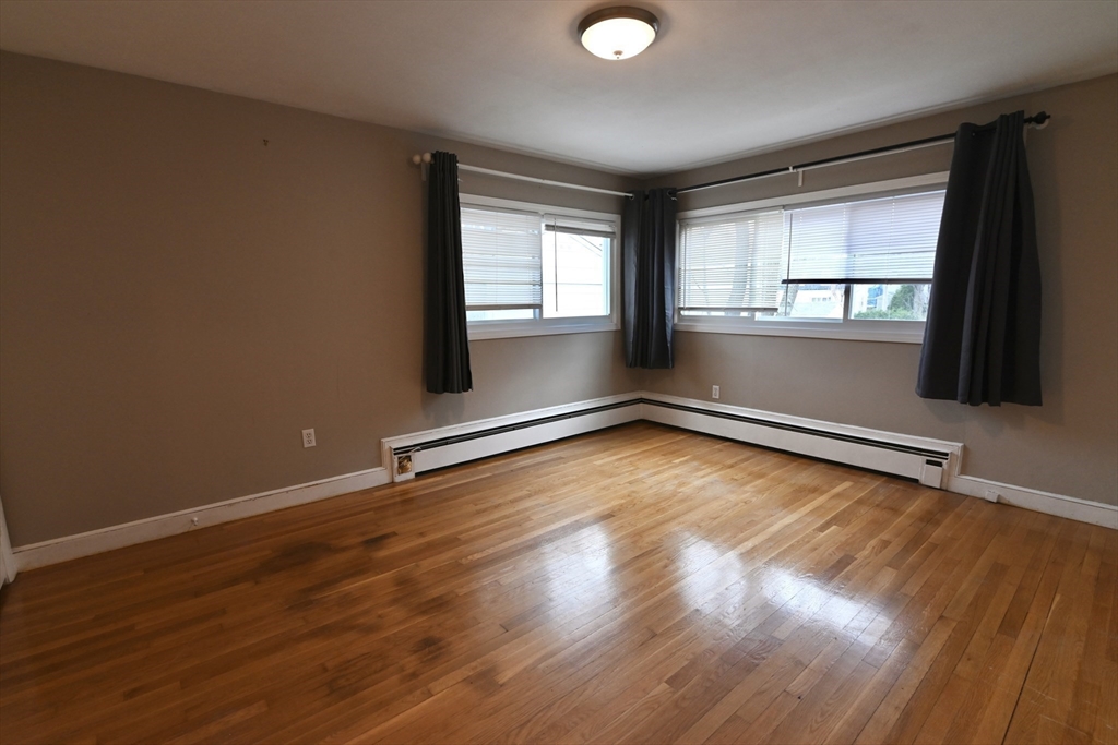 44-42 Farquhar Road, Unit 1 Newton, MA 02460 - Photo 7 of 11 a view of an empty room with wooden floor and a window