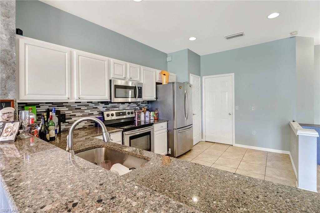 977 Hampton Circle, Unit 118 Naples, FL 34105 - Photo 4 of 24 a kitchen with stainless steel appliances granite countertop a refrigerator a stove a sink and a microwave