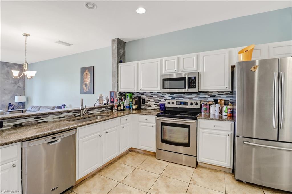 977 Hampton Circle, Unit 118 Naples, FL 34105 - Photo 5 of 24 a kitchen with white cabinets sink and stainless steel appliances