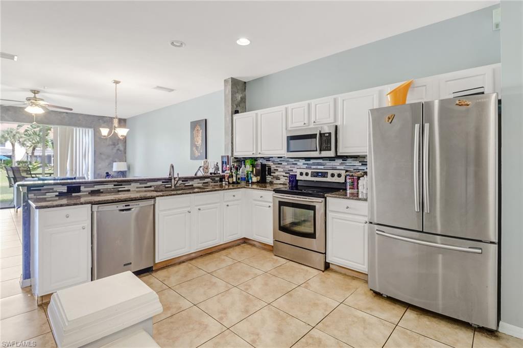 977 Hampton Circle, Unit 118 Naples, FL 34105 - Photo 6 of 24 a kitchen with white cabinets and stainless steel appliances